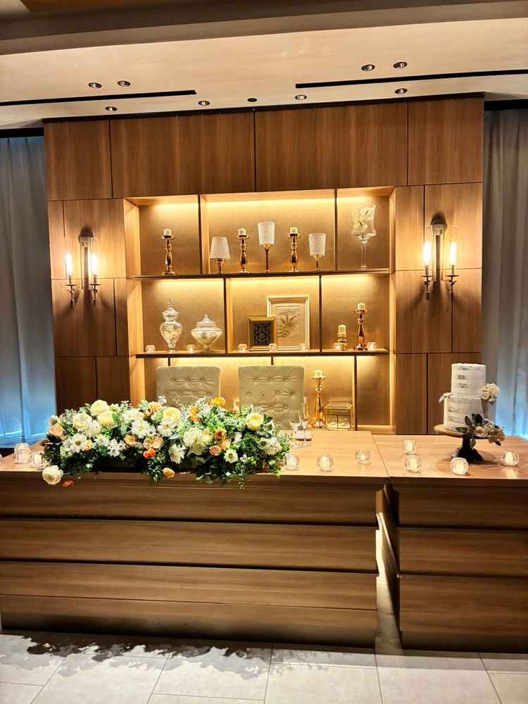 披露宴会場の高砂。三面窓の明るい会場の中で、高砂の背面は壁と装飾があり、逆光への配慮を感じた。