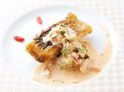 パリッと焼いたスズキのポアレ 旨みいっぱいの貝類とセミドライトマトのクリームソース