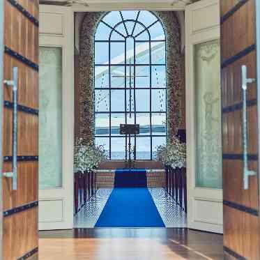 リヴァージュブラン 祭壇の先に海と空を一望するチャペル。大きな窓から光が降り注ぎ、海へ続くバージンロ