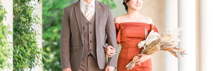 ブラウンのタキシードを着た新郎とテラコッタのカラードレスを着た新婦