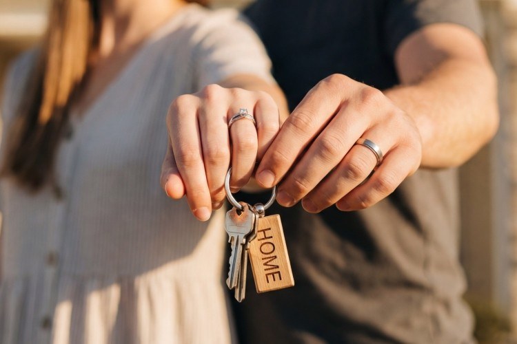 結婚指輪を着けた夫婦が家の鍵を持つ様子